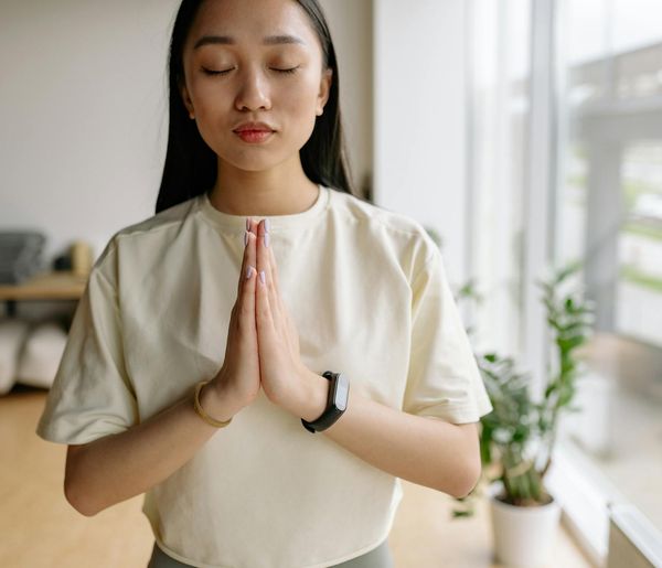 A person meditating in a serene, minimalist room with natural light.